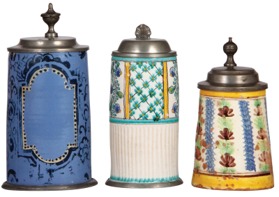 Three faience steins, 7.7" ht. to 9.2" ht., 1800s, pewter lids and first two have footrings, they display well, but first  has wear [cold-fired] and a 2" chip glued back in place, second in good condition, third has heavy glaze loss inside and outside. 