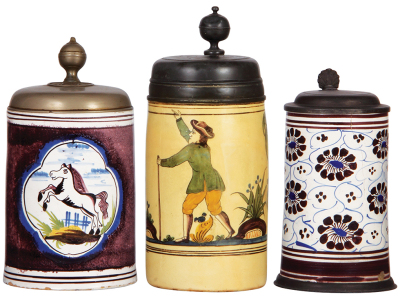 Three Faience steins, 8.2" ht. to 10.5" ht., late 1700s to early 1800s, Hannoversch Mündener Walzenkrug & two others, all have pewter lids, third has a pewter footring, first has three long hairlines & small rim chips, second lid has touch mark & inscript